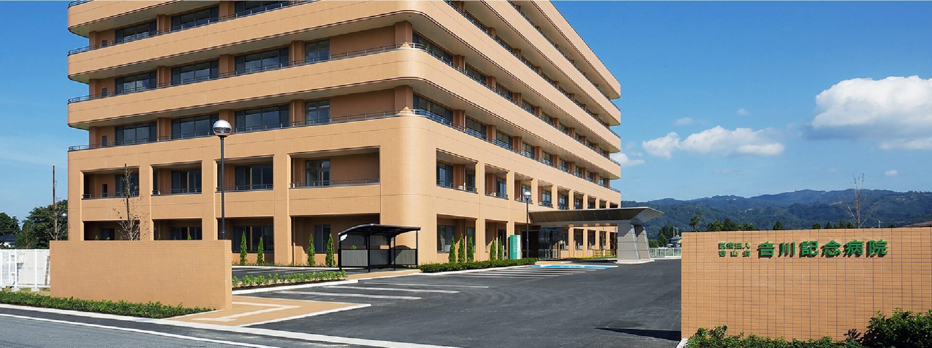 介護施設の建物外観。複数階の大規模施設で、玄関車寄せと施設名看板が見える。